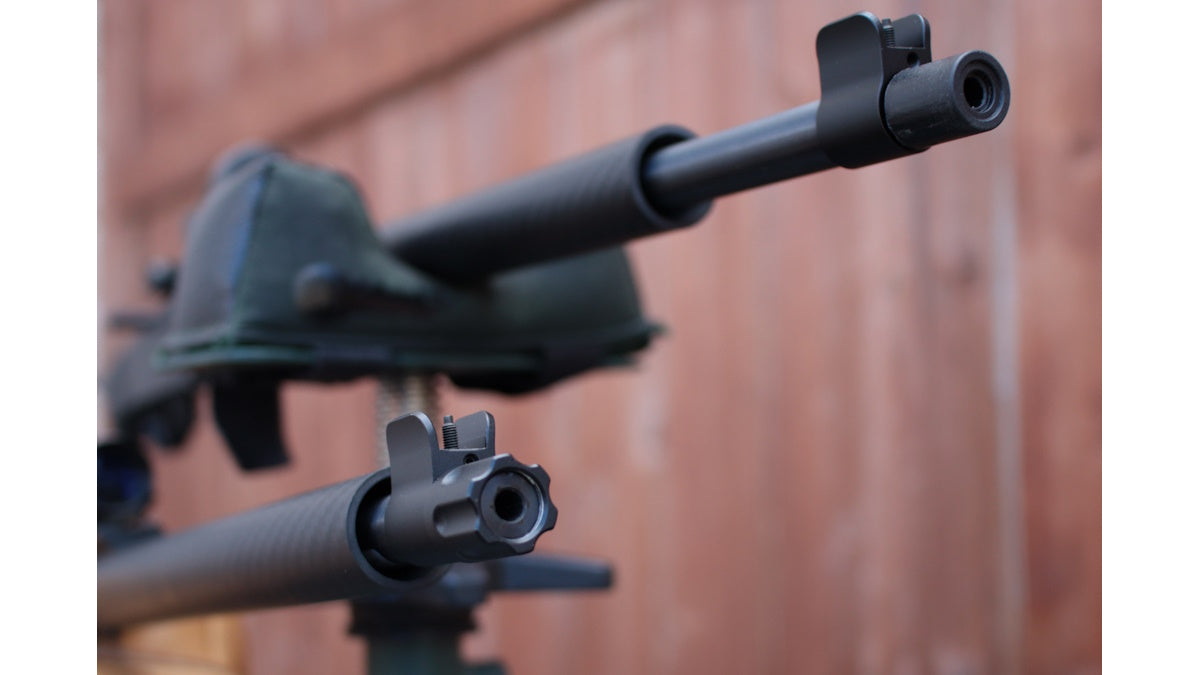 A close-up of a rifle with iron sights and a Picatinny rail attached to the barrel.